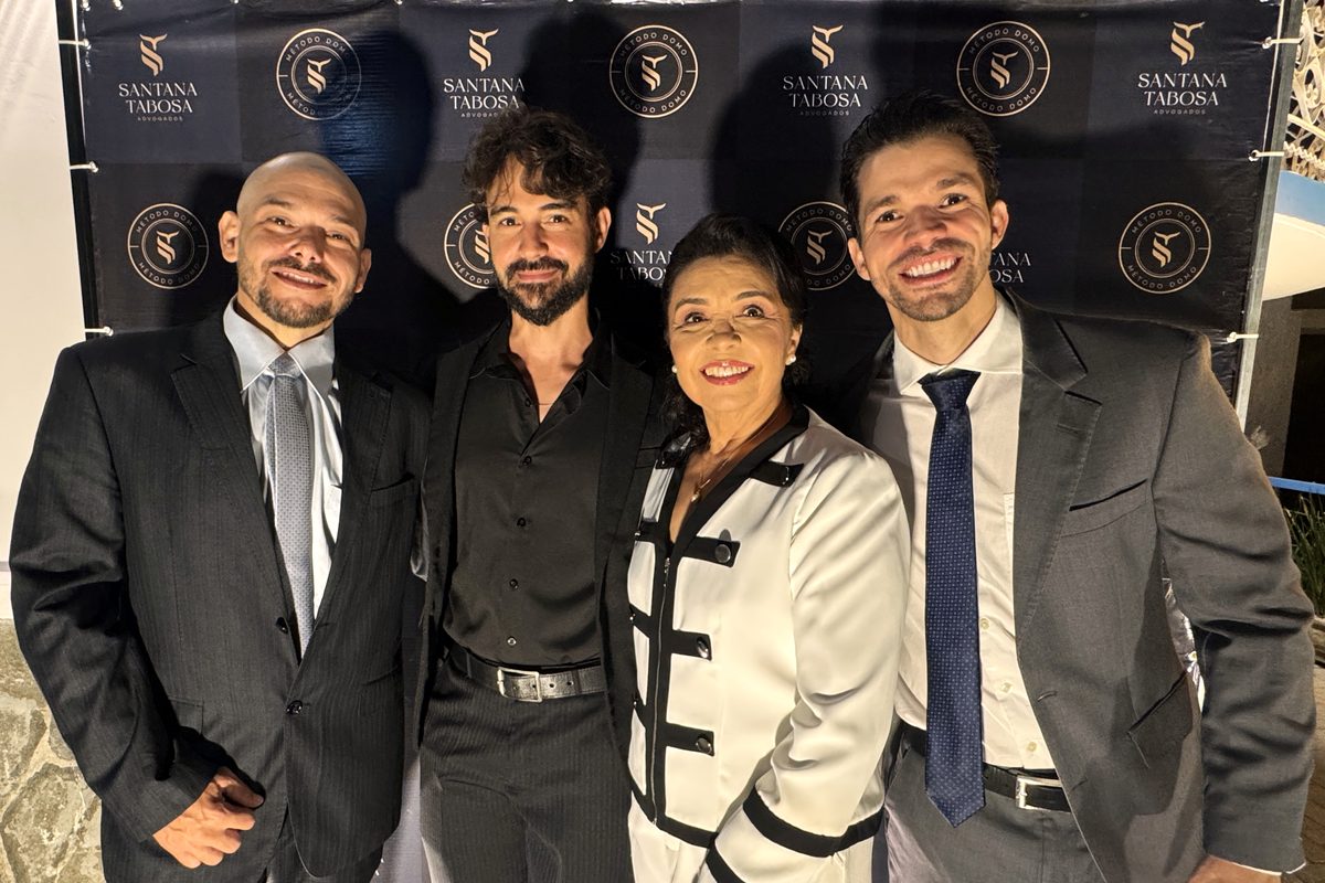 Teresa Tabosa acompanhada de três convidados diante do painel do evento